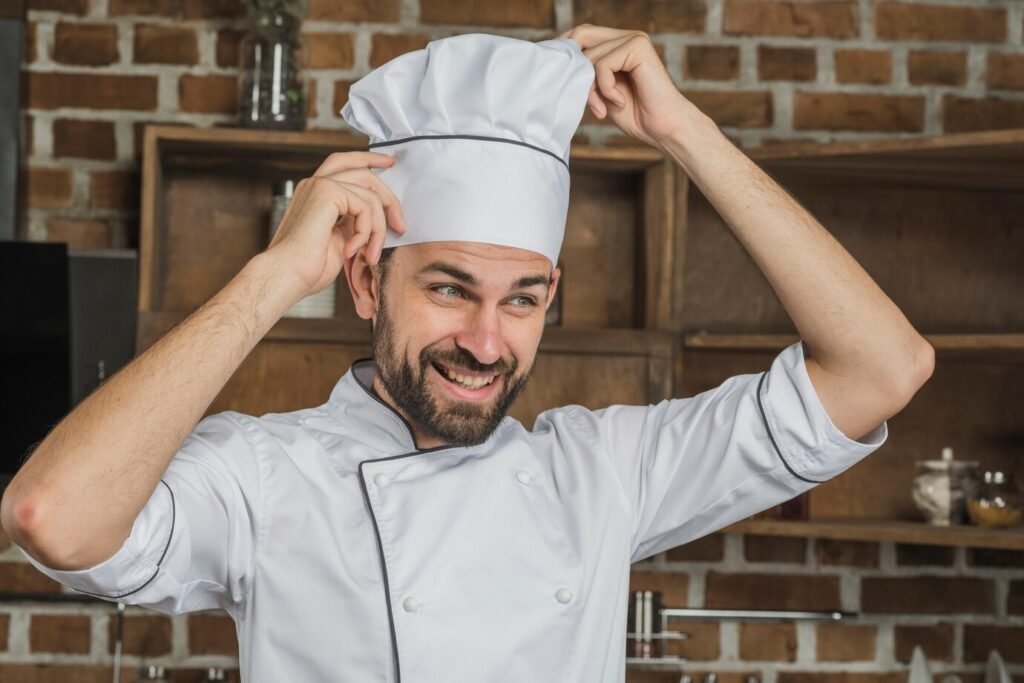 Curtis adjusting his chef hat and smiling confidently